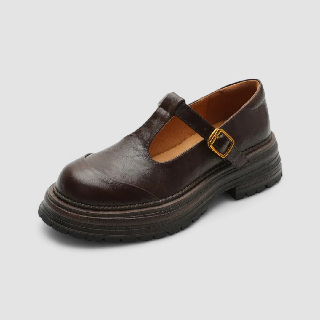 Woman wearing brown Mary Stacey comfort shoes with a T-strap, standing on a city footpath.
