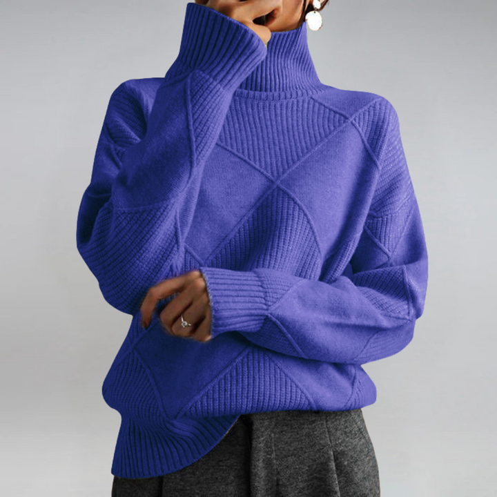 A woman in a stand-collar sweater with an elegant drape, styled with tailored pants.