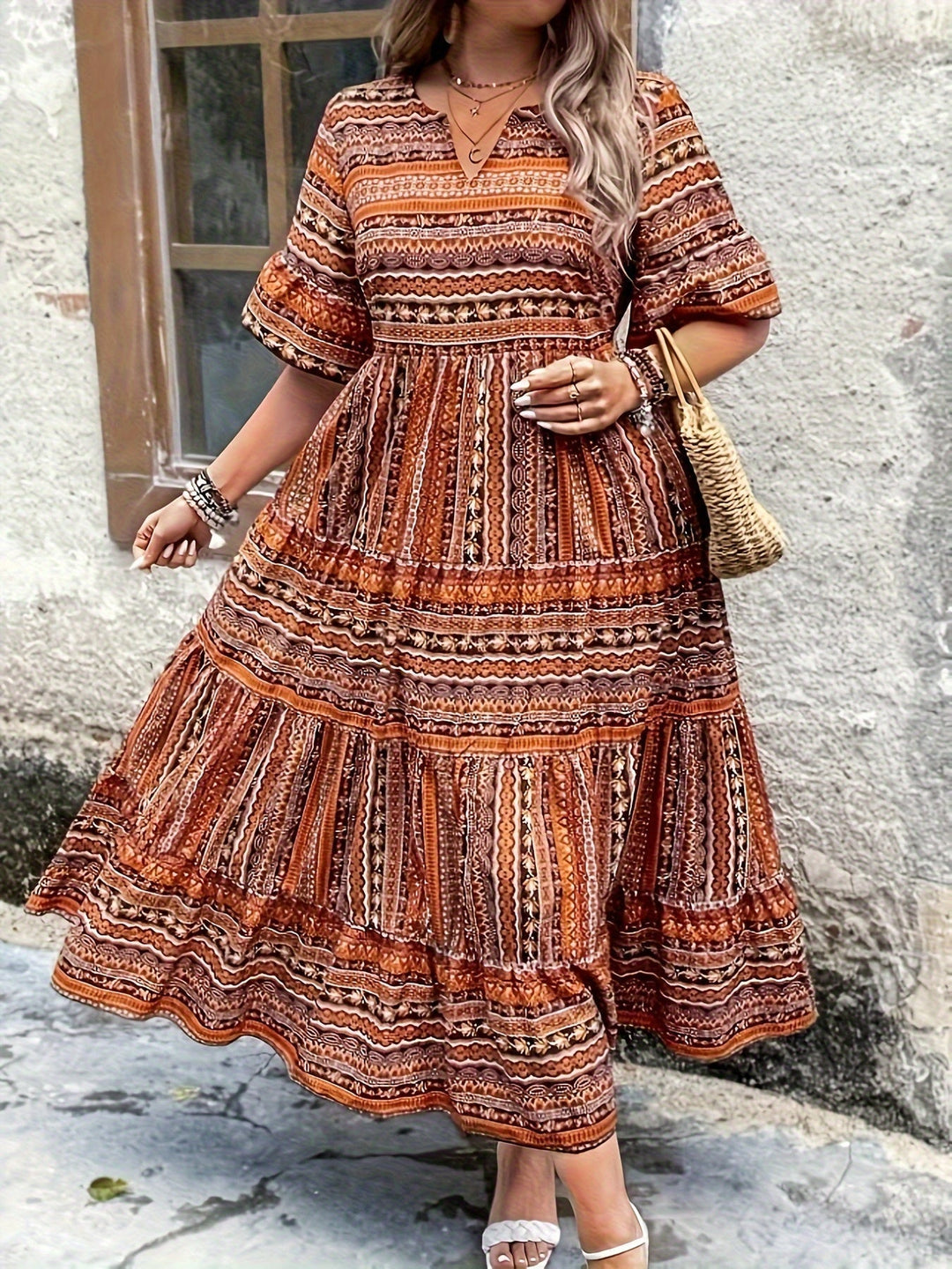 Woman wearing a flowing bohemian maxi dress with intricate pattern and ruffled details.
