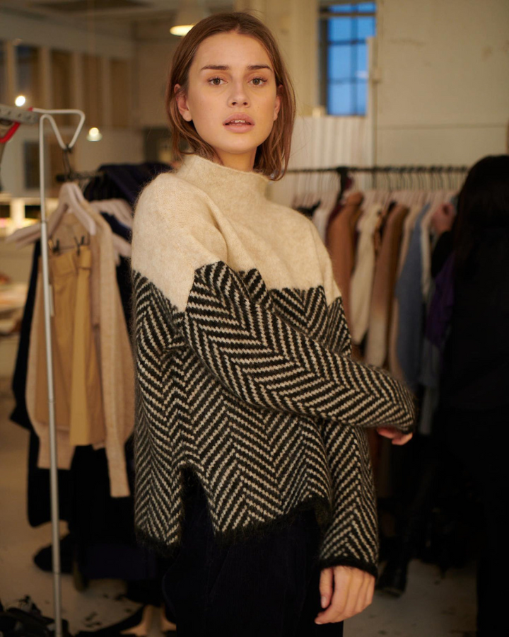A woman wearing a zigzag-pattern funnel neck sweater styled elegantly for an fall day out.