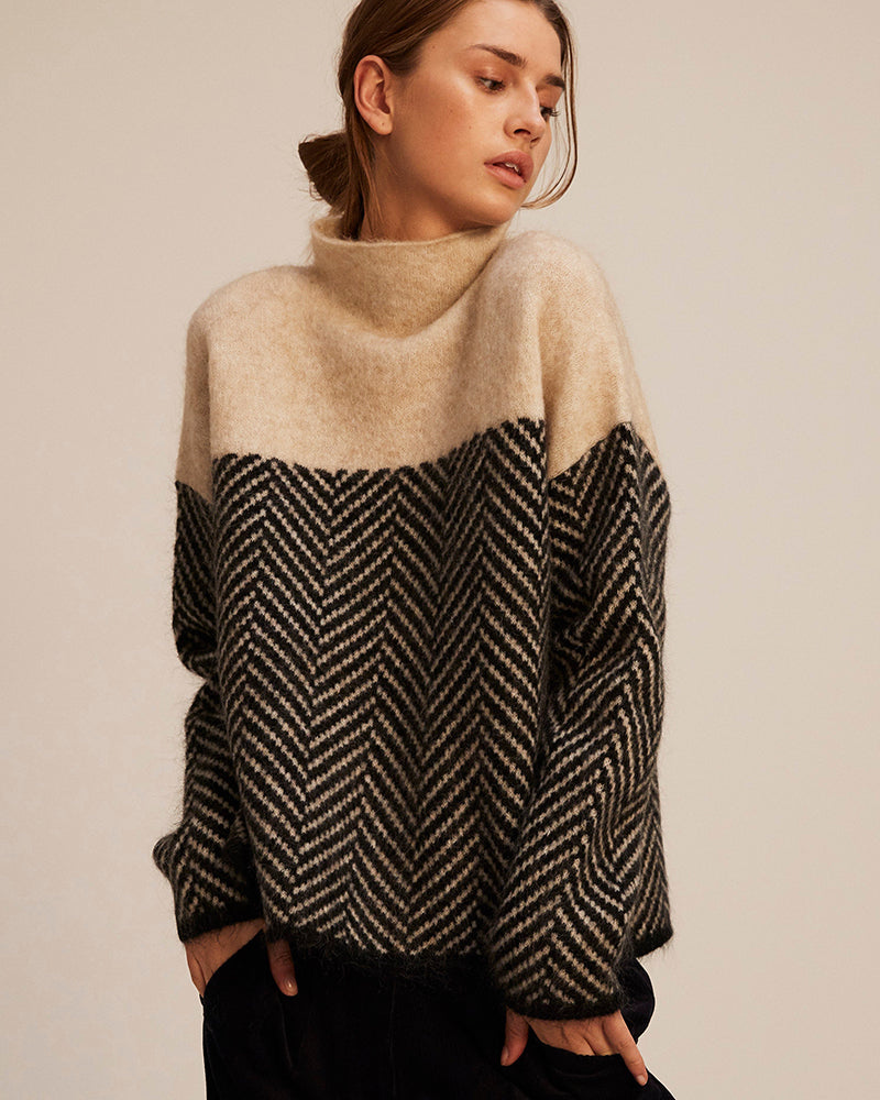 A woman wearing a zigzag-pattern funnel neck sweater styled elegantly for an fall day out.