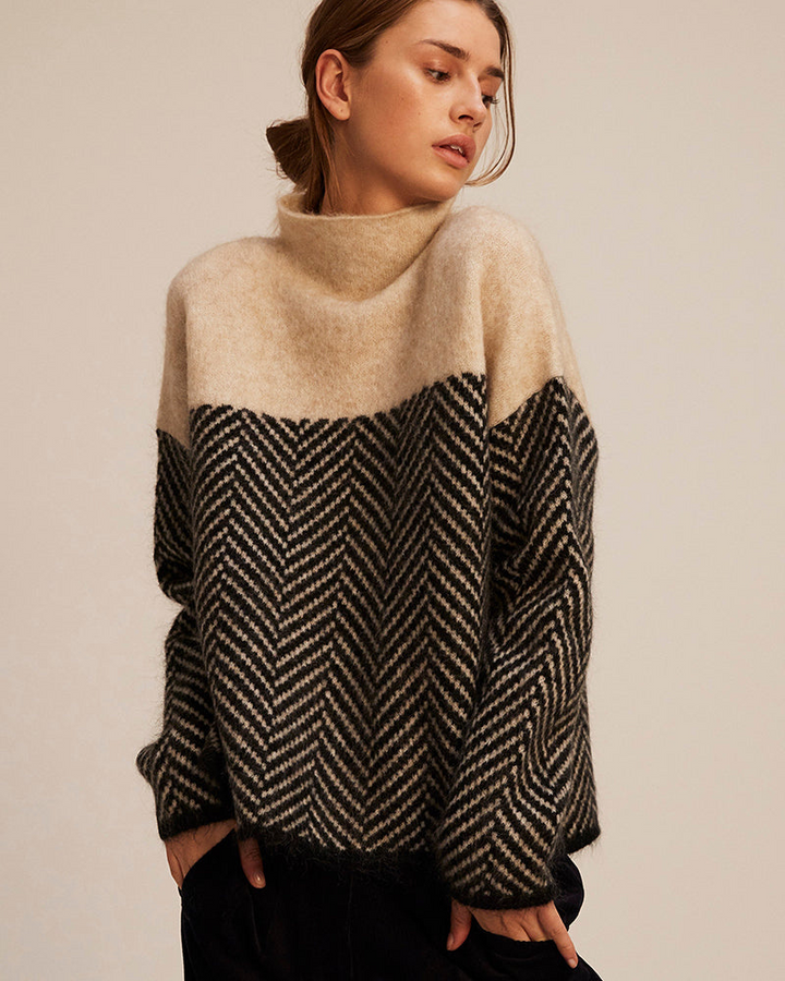 A woman wearing a zigzag-pattern funnel neck sweater styled elegantly for an fall day out.