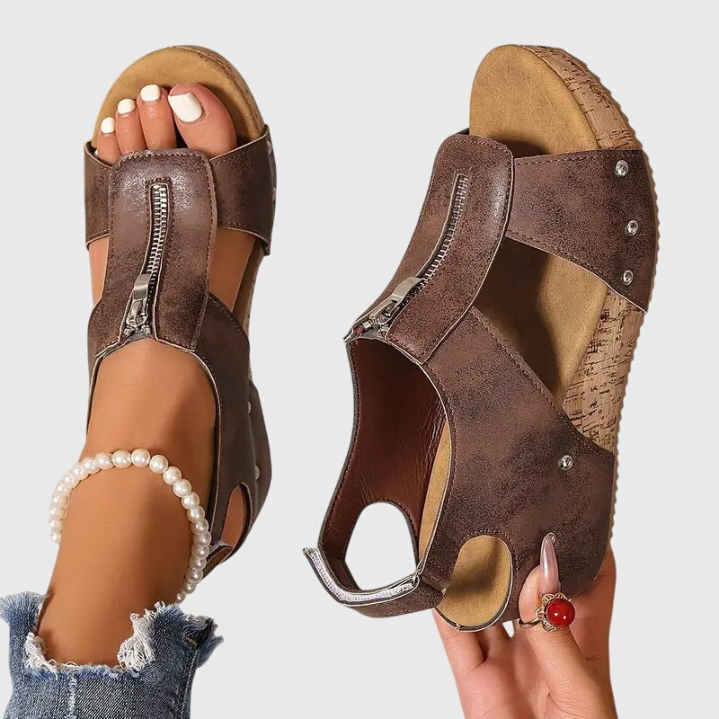 A woman wearing black zip-front wedge sandals with a cushioned footbed and open toe.
