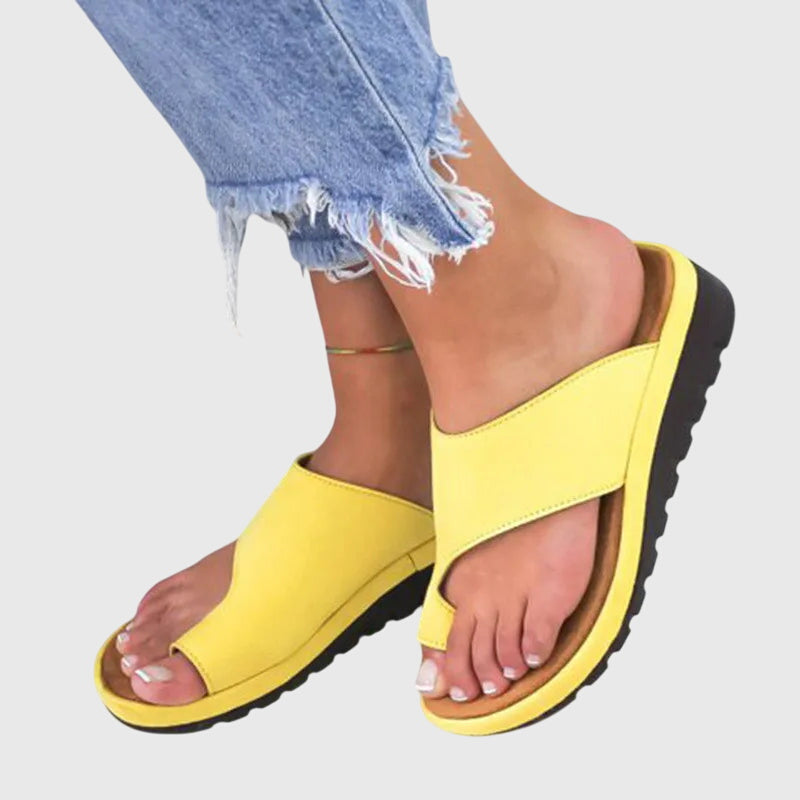 A woman in taupe toe-loop supportive sandals standing gracefully, feet cushioned and at ease.