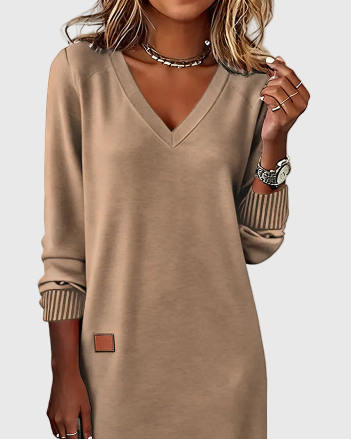 Woman wearing the Susan flowing elegant dress in beige, standing relaxed and smiling.