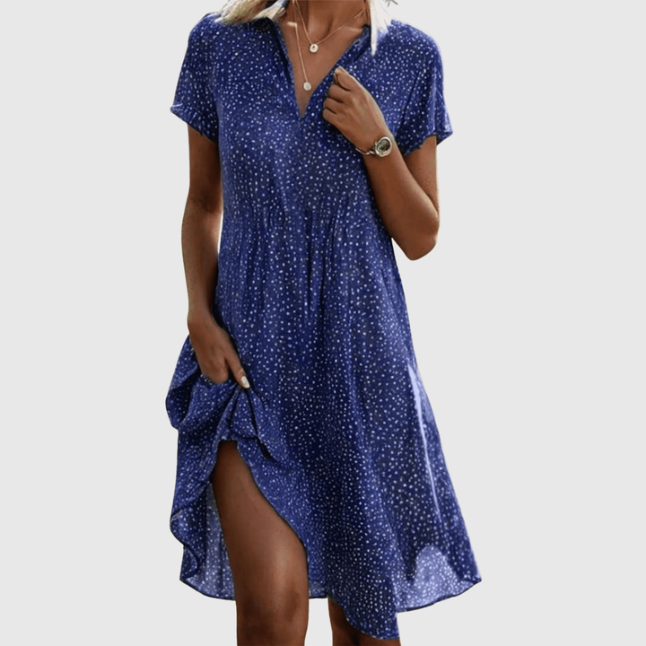 Woman wearing the Cynthia speckled summer dress in green, smiling in the sunshine outdoors.