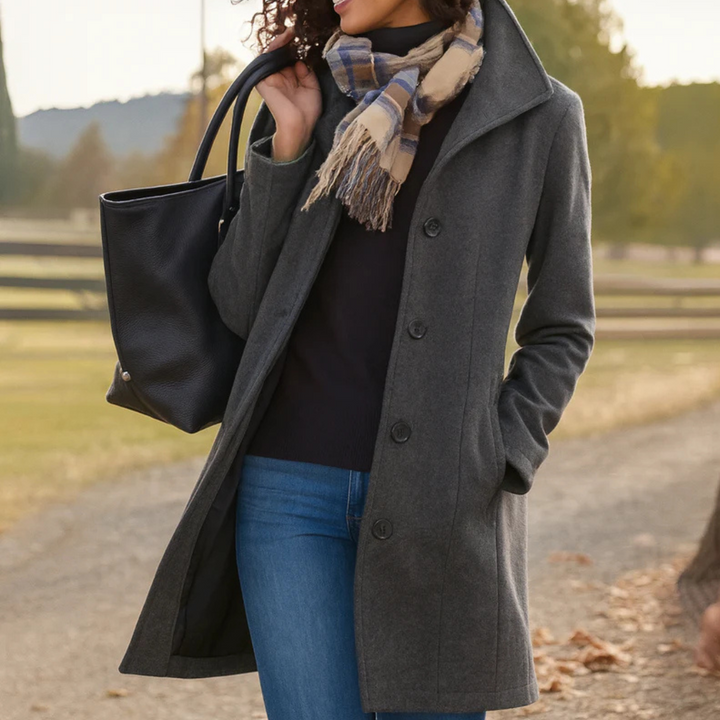 A woman wearing an elegant camel button-through coat over a sweater on a crisp fall day.