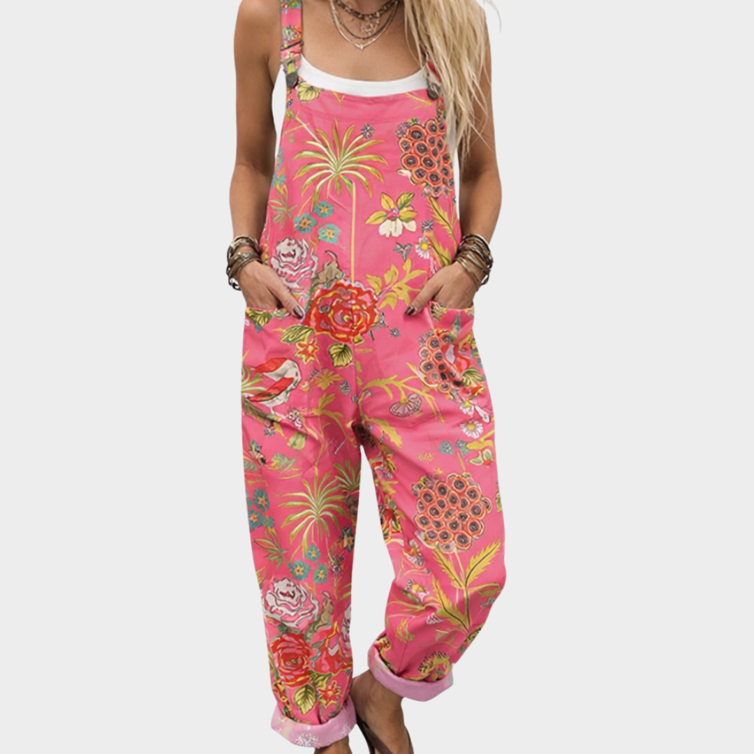 Woman wearing bright coral pink overalls with a tropical bloom and palm print, adjustable straps, cheerful and relaxed.