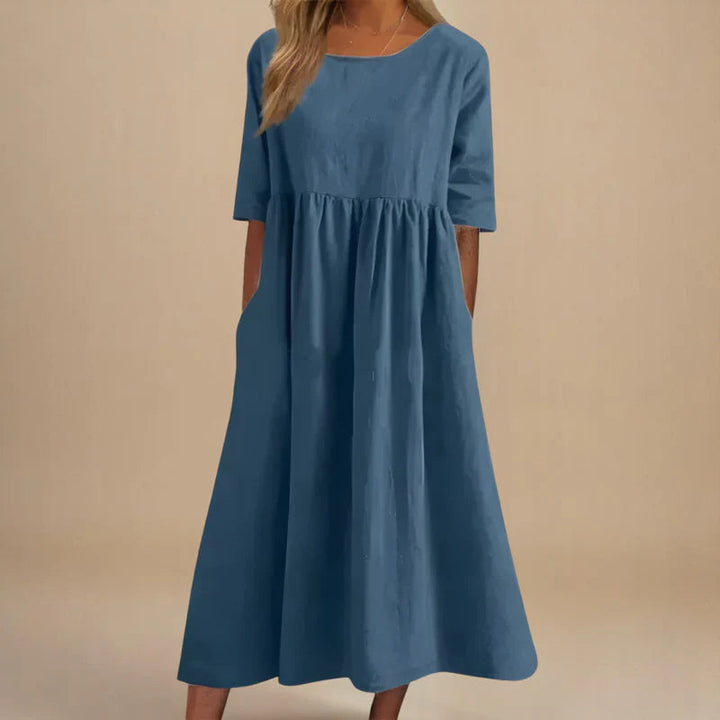 A woman wearing the Shannon flowing day dress with a gathered waist and elbow-length sleeves.