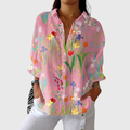 A woman wearing a flowing colourful printed blouse with an elegant button front, styled with a skirt for a relaxed outing.
