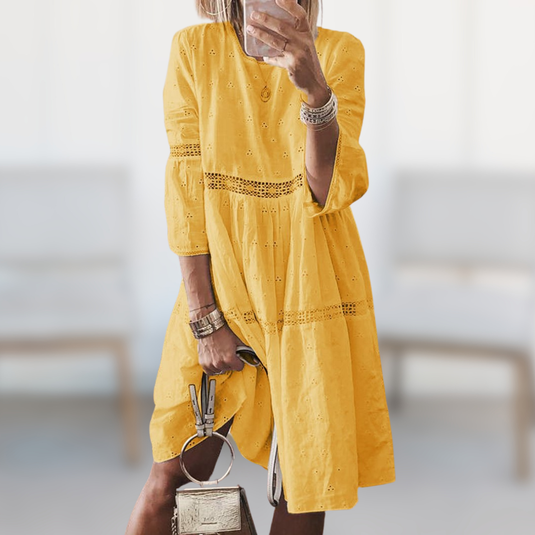 Woman wearing the Megan™ elegant summer dress with a round neckline and flowing silhouette, standing outdoors on a sunny day.