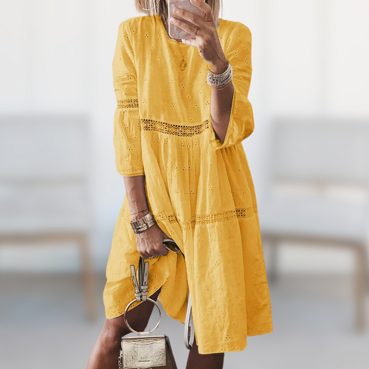 Woman wearing the Megan™ elegant summer dress with a round neckline and flowing silhouette, standing outdoors on a sunny day.