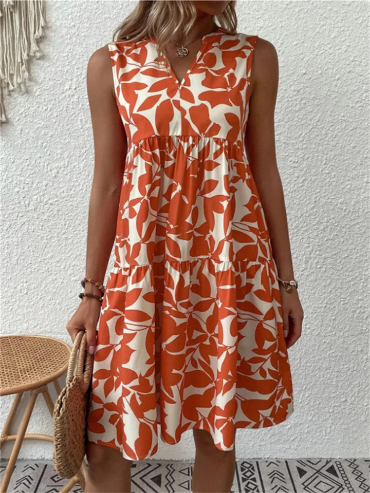 Woman wearing the Deborah sleeveless leaf-print midi dress in green, relaxing outdoors on a warm afternoon.