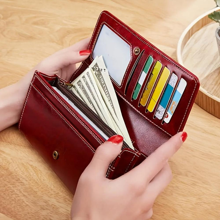 A woman holding a long flap-over wallet, tucking a card into its slot.