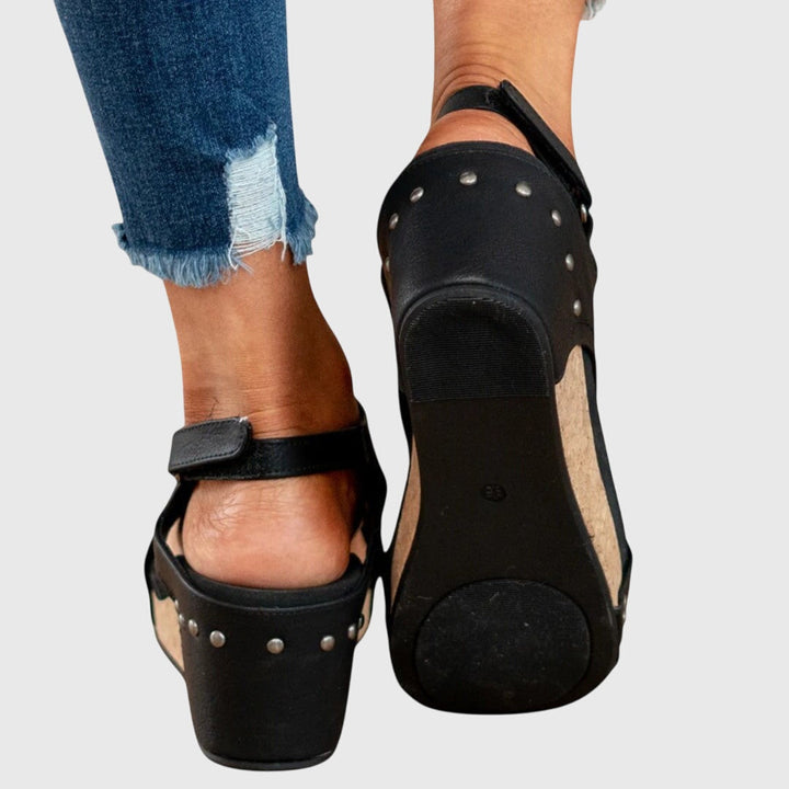 A woman in taupe wedge sandals with an open front, out shopping on a warm day.