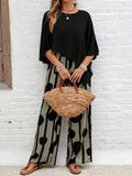 A woman wearing a draped asymmetric top with printed high-waisted wide-leg pants.