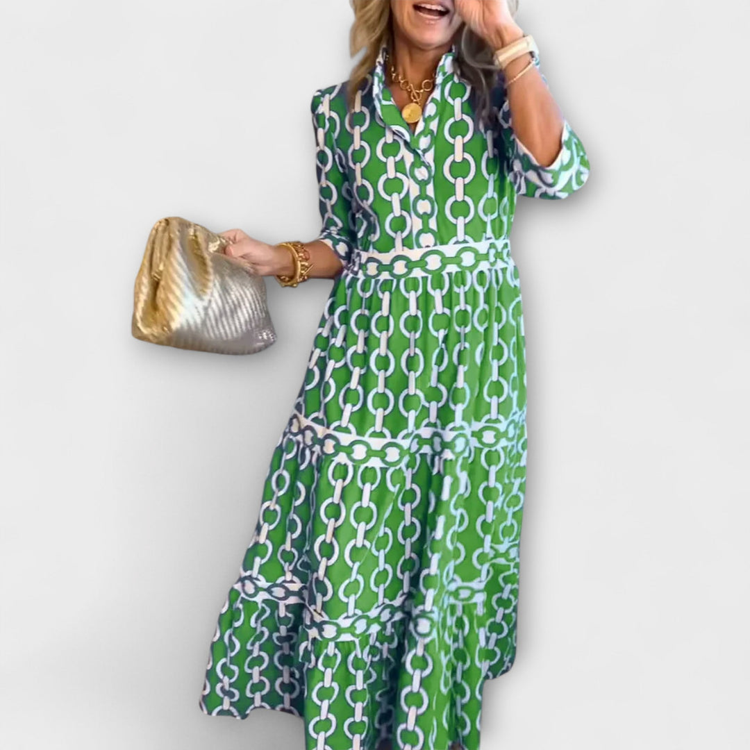A woman wearing a flowing chain print midi dress that drapes elegantly as she walks.