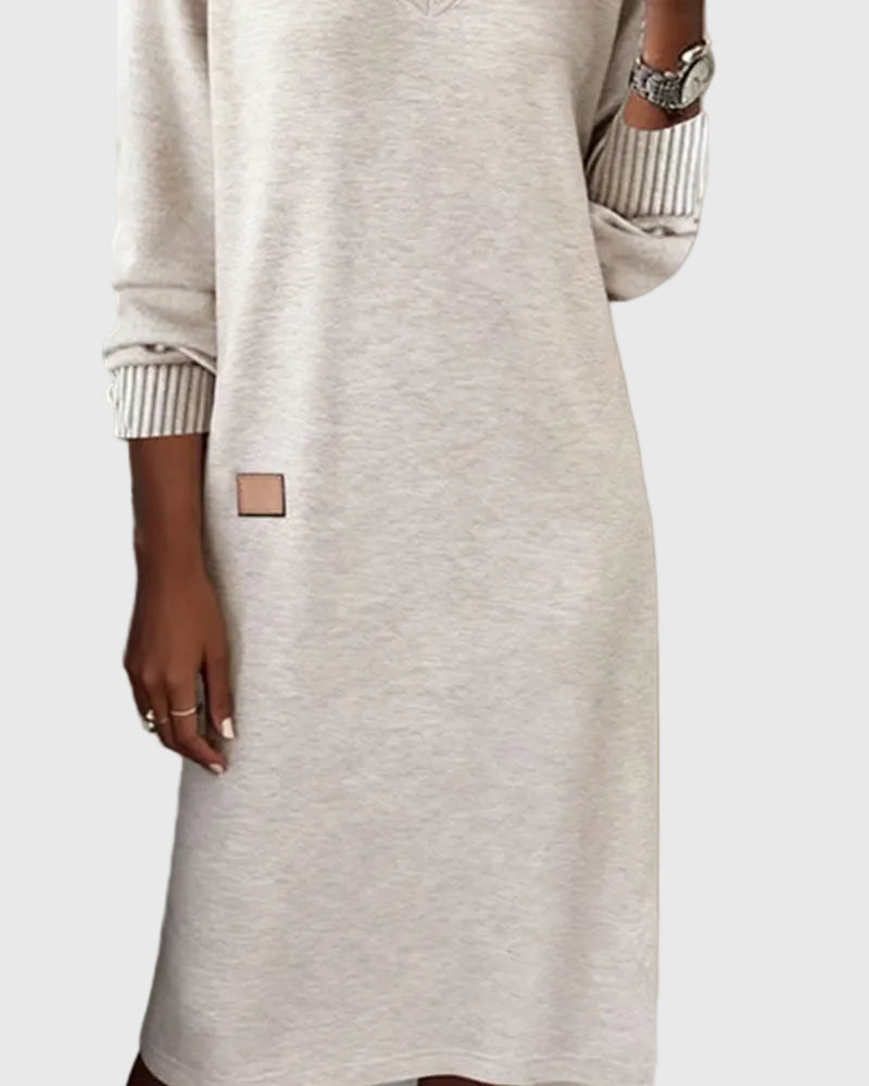 Woman wearing the Susan flowing elegant dress in beige, standing relaxed and smiling.