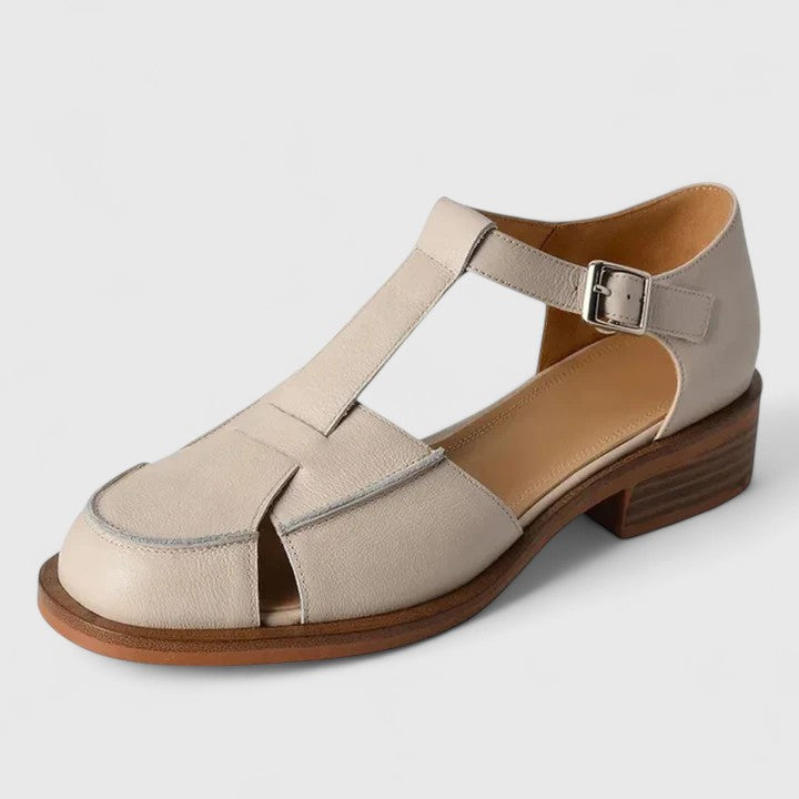 A woman wearing brown Mary Jane sandals with a T-strap and buckle, paired with a summer dress.