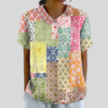 A woman wearing a flowing polo collar top in a colourful patchwork print, looking relaxed and well dressed.