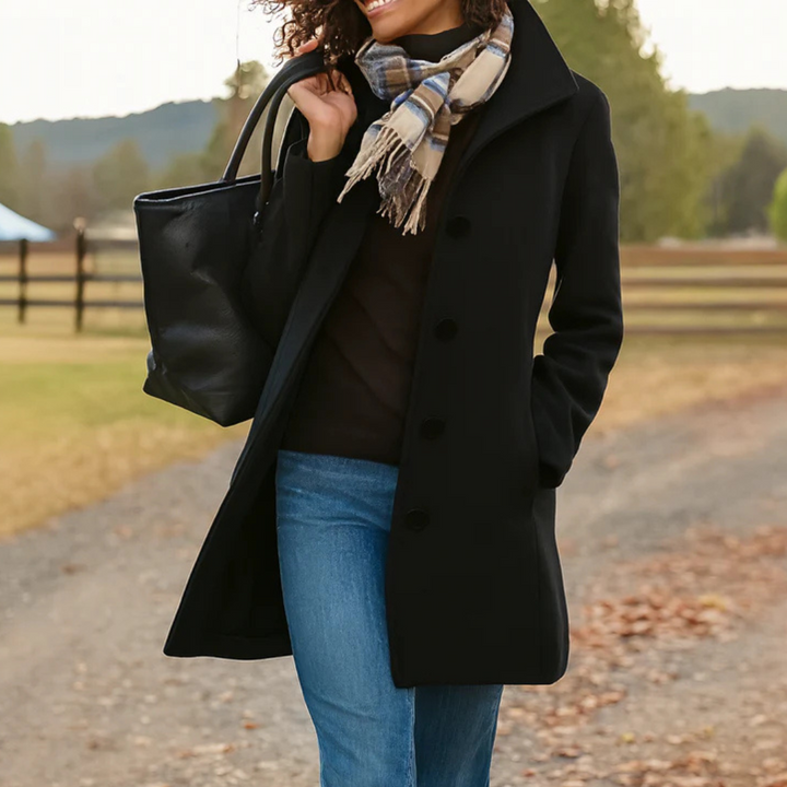 A woman wearing an elegant camel button-through coat over a sweater on a crisp fall day.