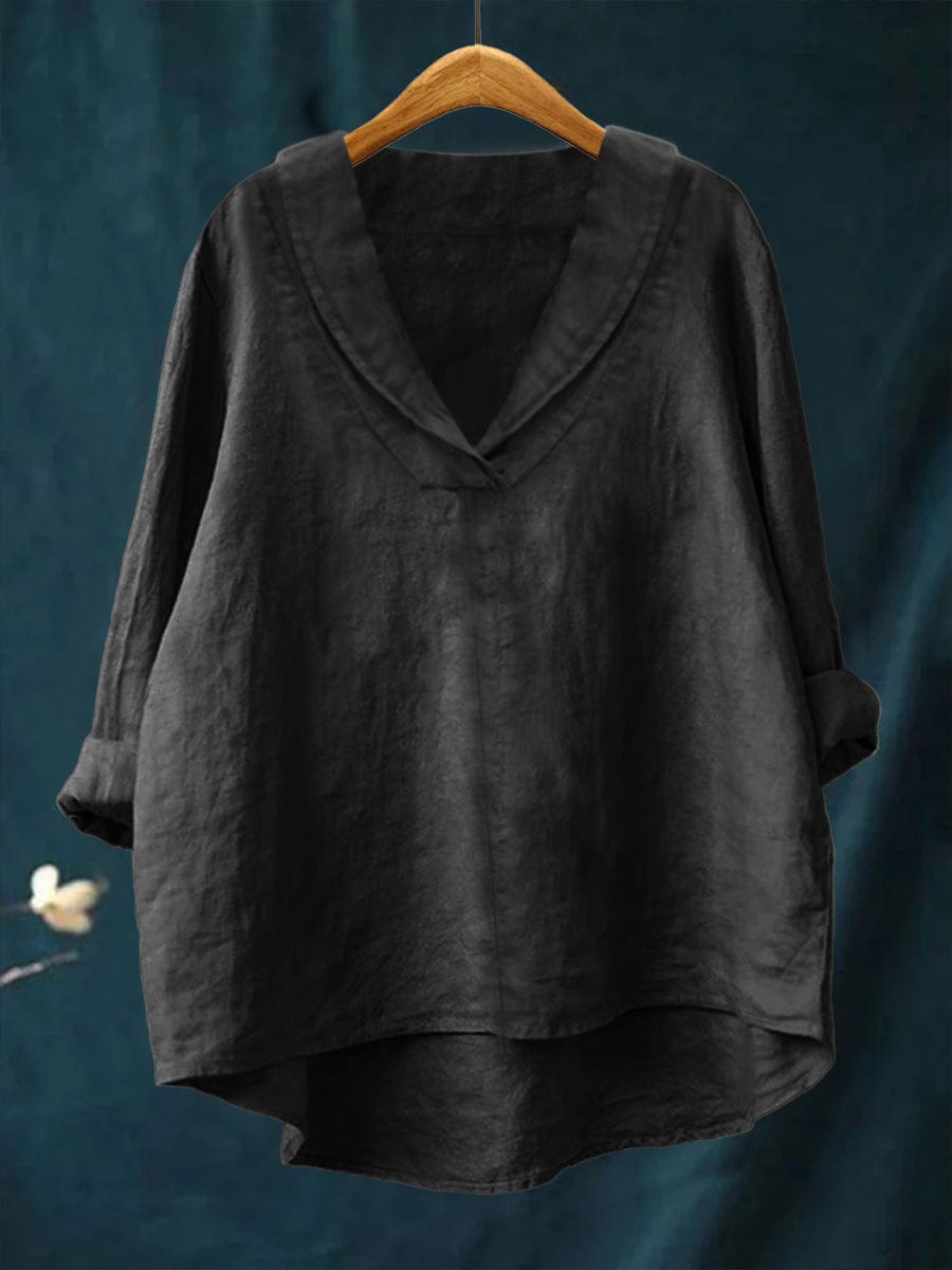 A woman wearing an elegant plain summer blouse with a flowing drape, styled with pants.