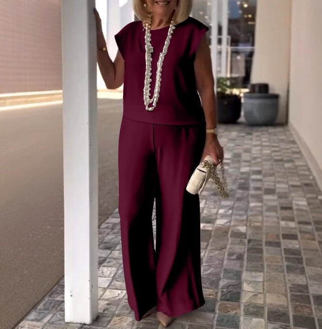 A woman wearing a flowing short-sleeve top with graceful wide-leg pants.