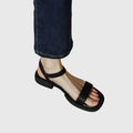 A woman in white square-toe ankle-strap sandals dressed for a summer brunch.
