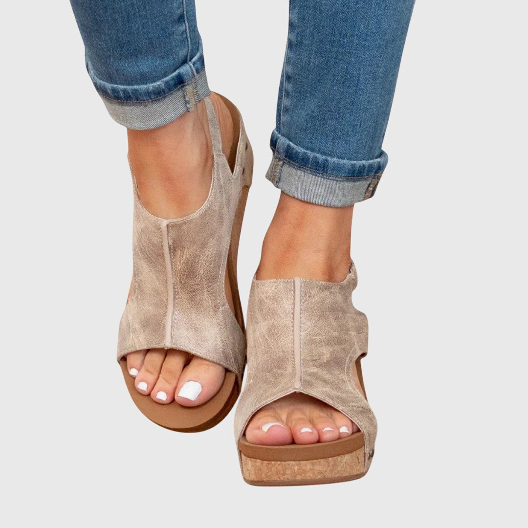 A woman in taupe wedge sandals with an open front, out shopping on a warm day.