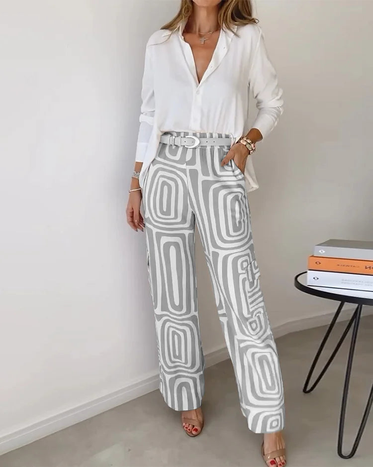 A woman wearing a plain button-up top with geometric-print pants and a belt at the waist.