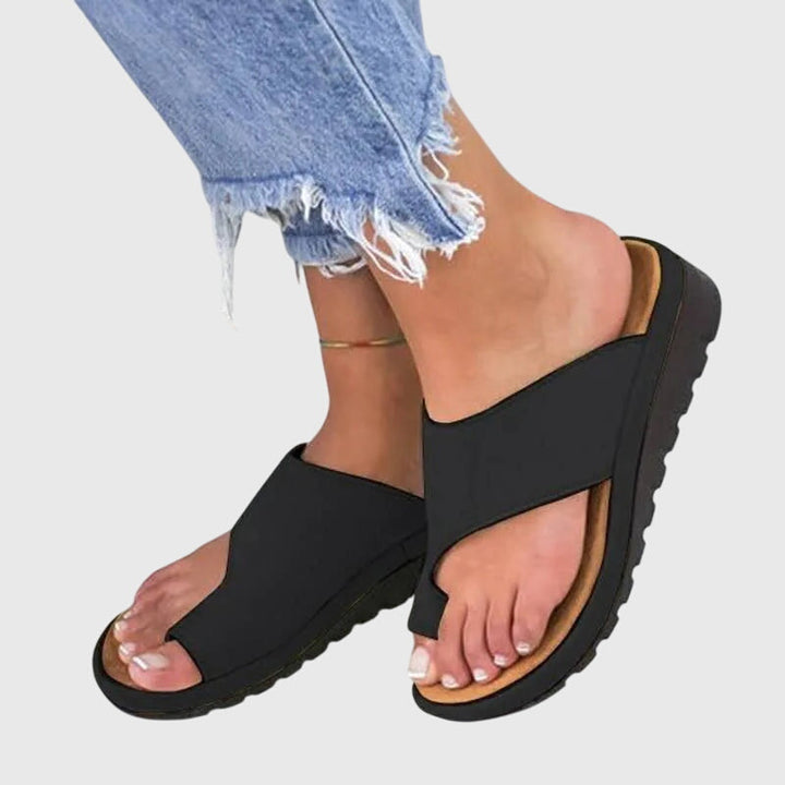 A woman in taupe toe-loop supportive sandals standing gracefully, feet cushioned and at ease.