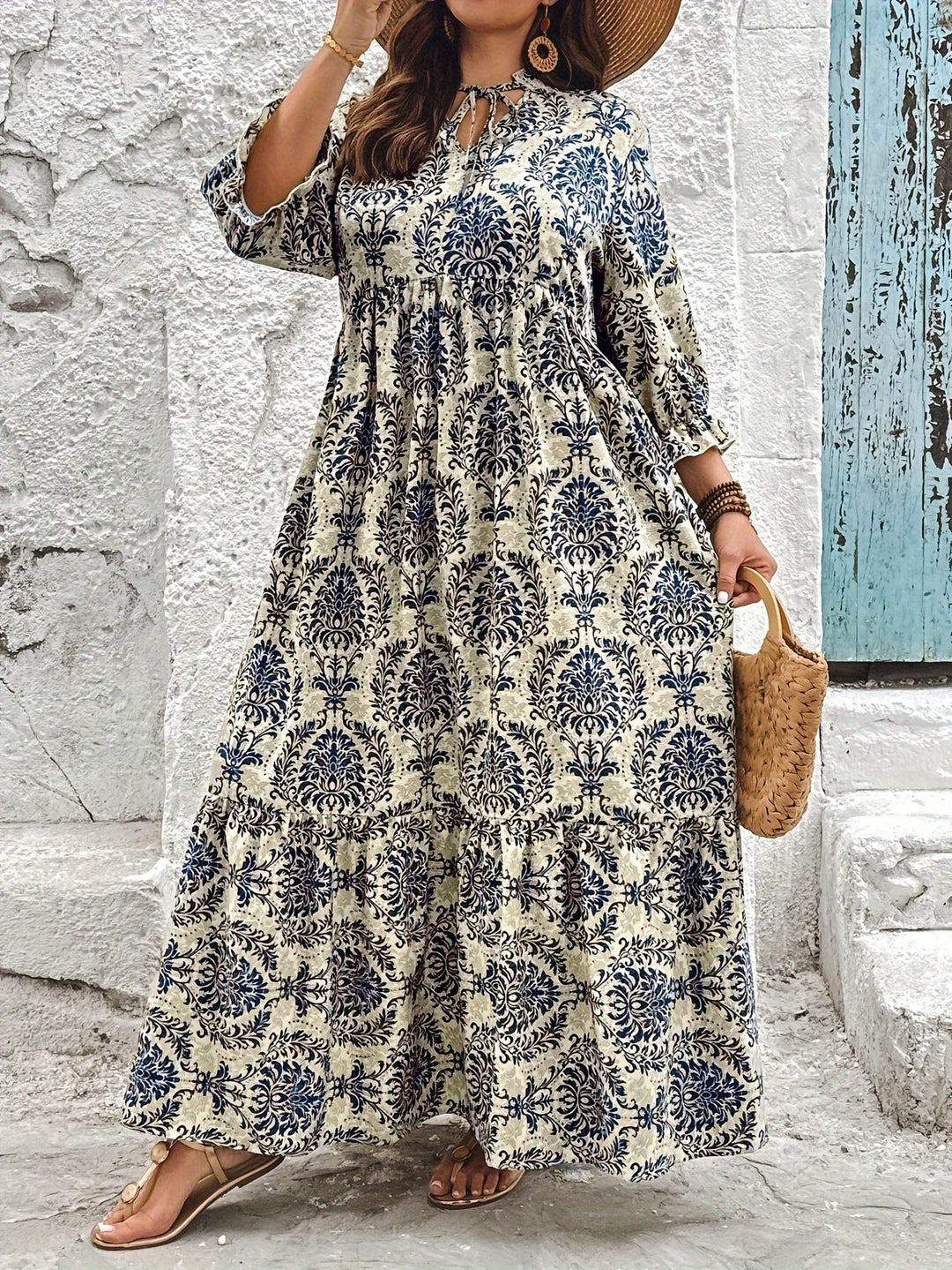 Woman strolling by the sea in the Melanie mosaic print maxi dress with a keyhole neckline and bow detail.