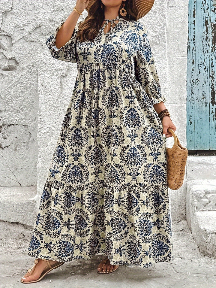 Woman strolling by the sea in the Melanie mosaic print maxi dress with a keyhole neckline and bow detail.