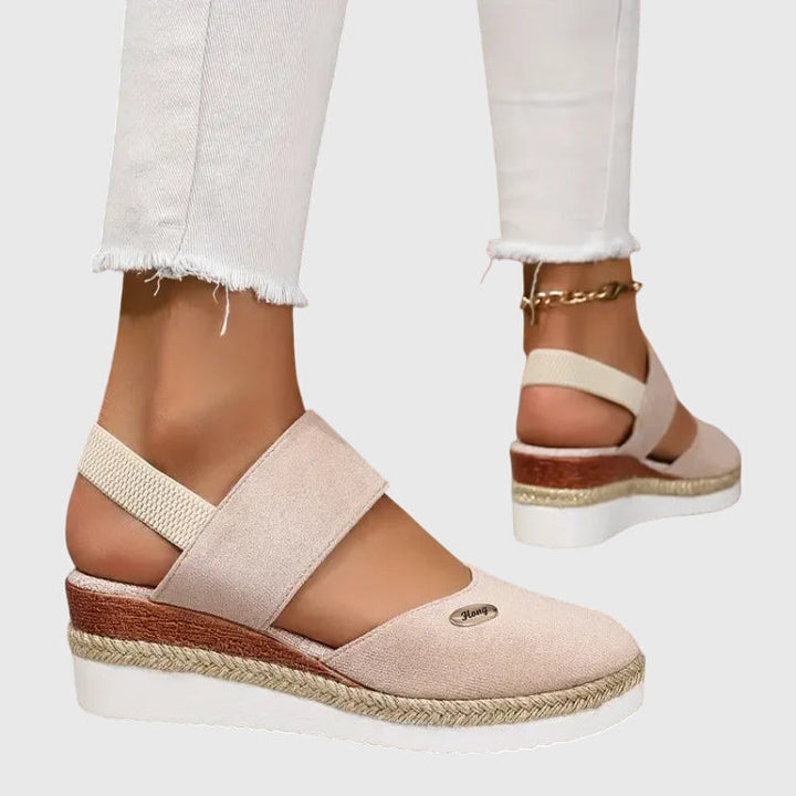 A woman wearing wide-fit supportive sandals with a summer dress, walking comfortably and looking assured.