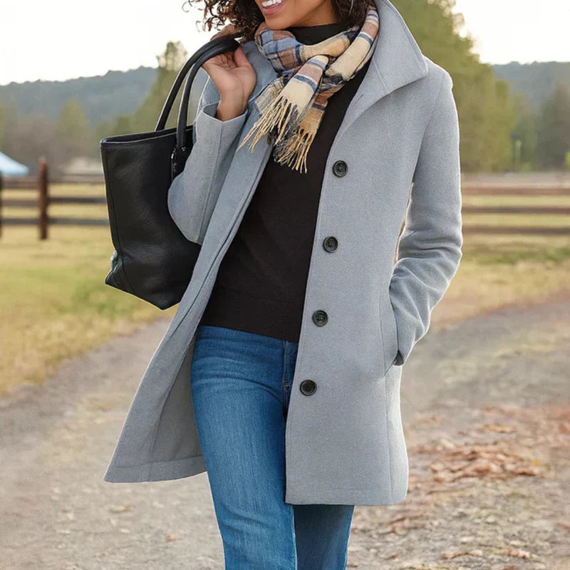 A woman wearing an elegant camel button-through coat over a sweater on a crisp fall day.