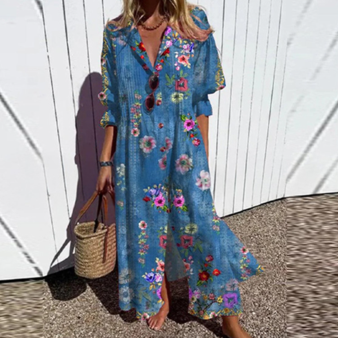 Woman wearing the Gail™ leaf print maxi dress with a button front, walking along the coast in a light breeze.