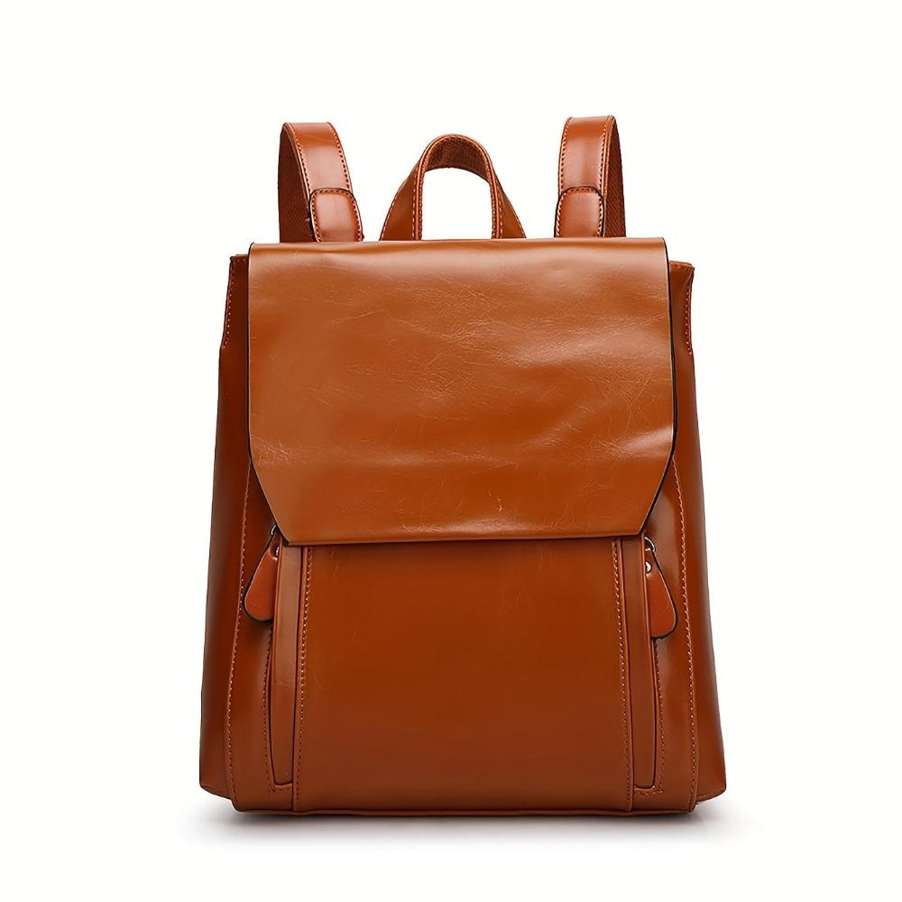 A woman wearing a padded vintage-style backpack over both shoulders while walking through the city.