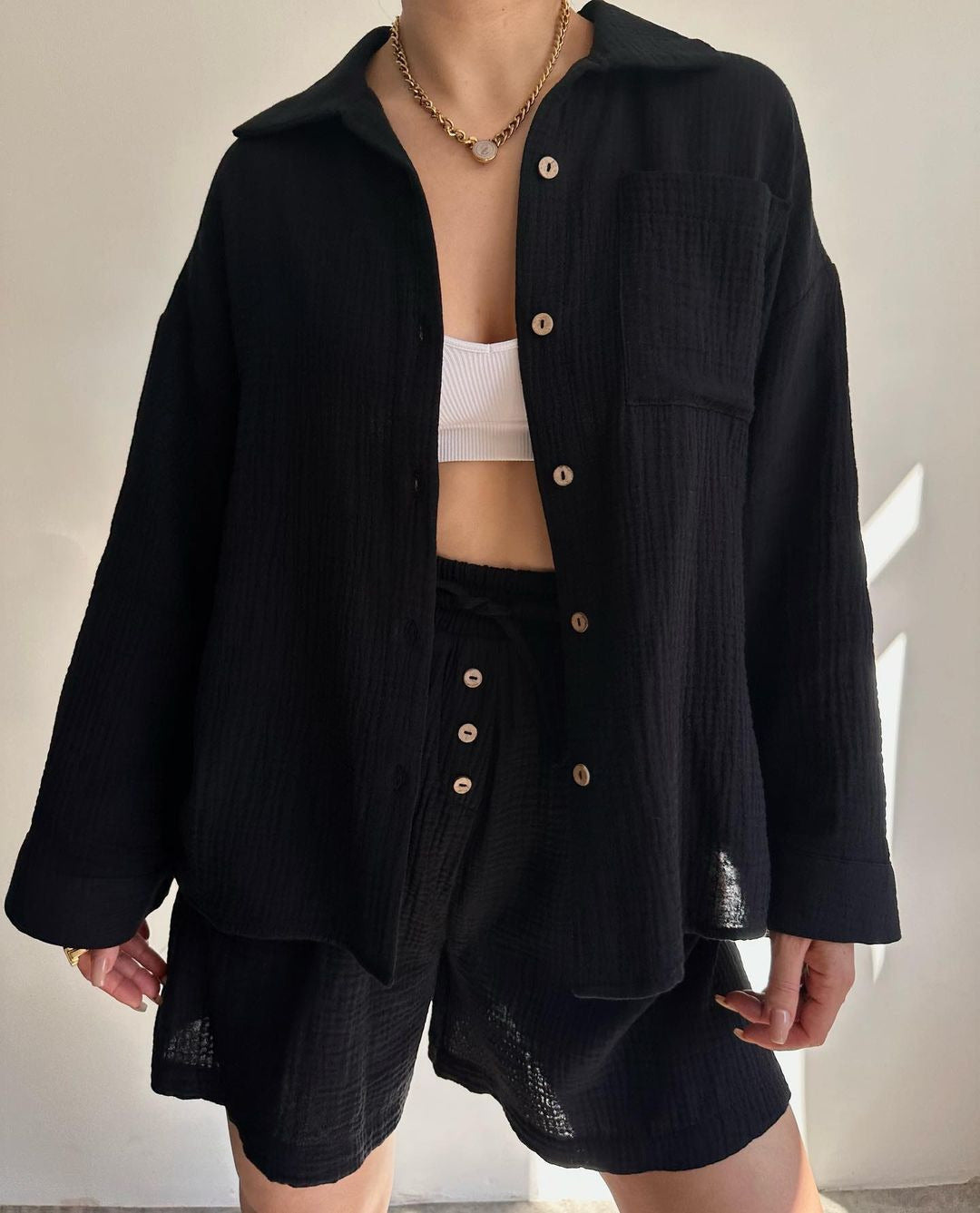 A woman wearing a flowing oversized shirt with drawstring shorts, relaxed and breezy.