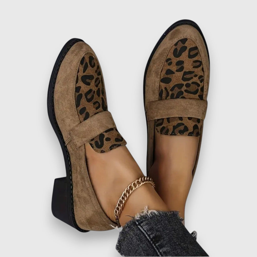 A woman wearing tan leopard print loafers with a low block heel, styled with jeans.