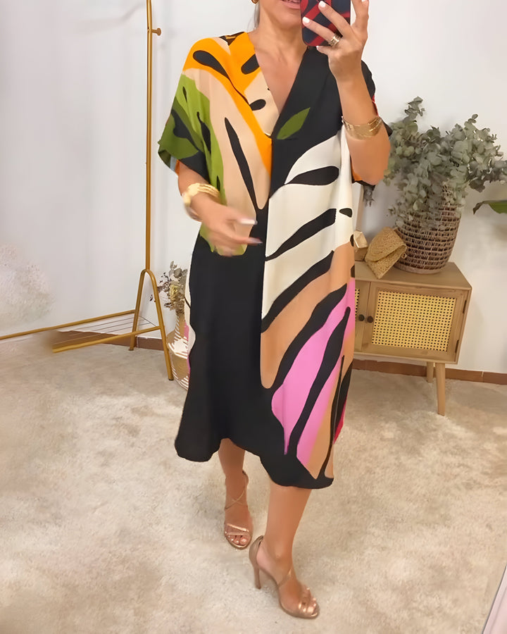 A woman wearing a colourful abstract print dress with a V-neckline and short sleeves.