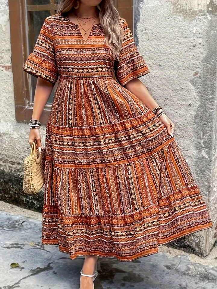 Woman wearing a flowing bohemian maxi dress with intricate pattern and ruffled details.