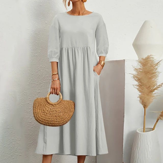 A woman wearing the Barbara fitted waist midi dress with three-quarter sleeves and a flowing skirt.