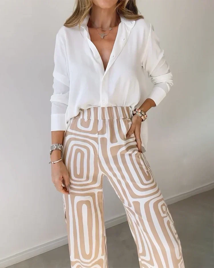 A woman wearing a plain button-up top with geometric-print pants and a belt at the waist.