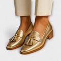 A woman wearing shimmering gold loafers with a festive outfit
