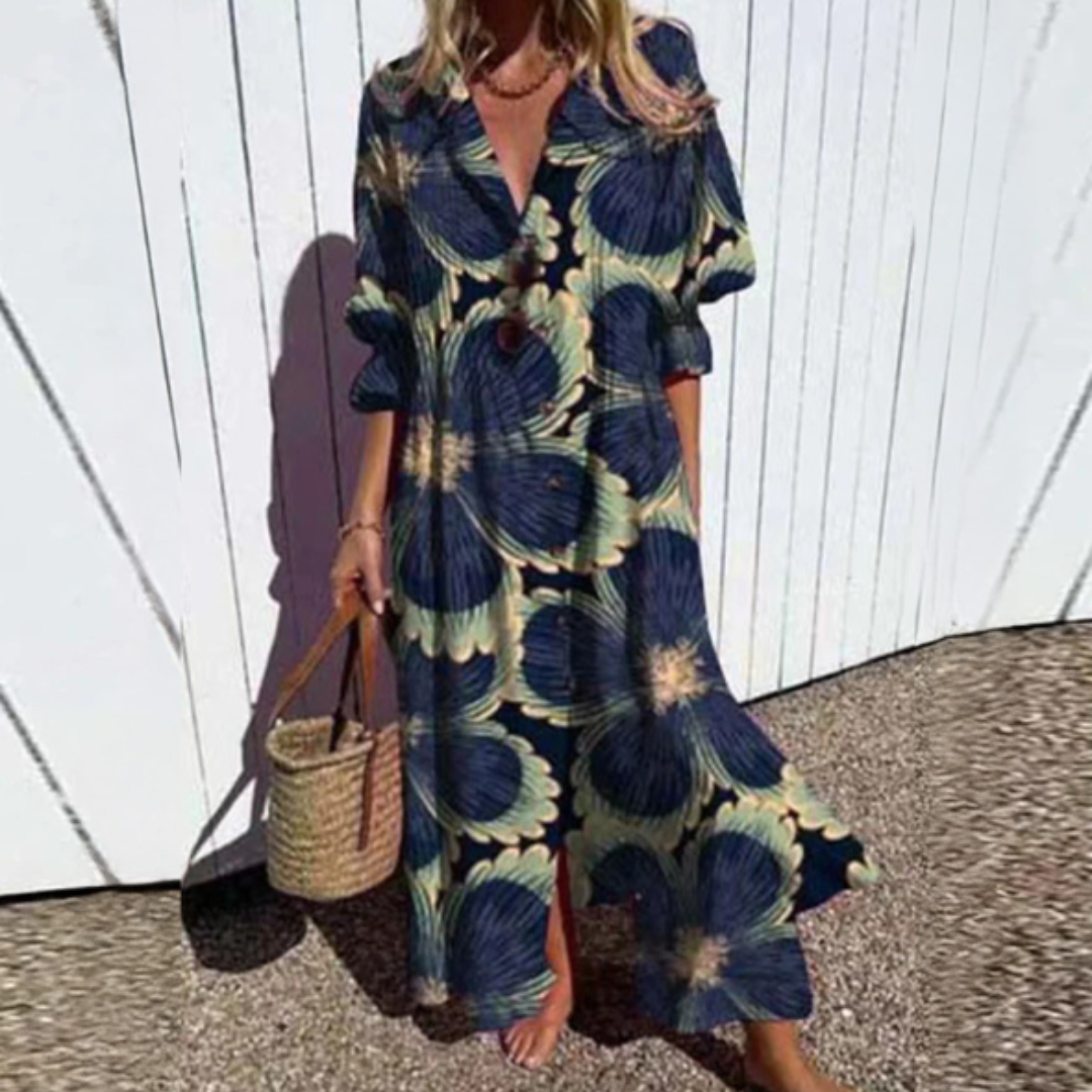 Woman wearing the Gail™ leaf print maxi dress with a button front, walking along the coast in a light breeze.