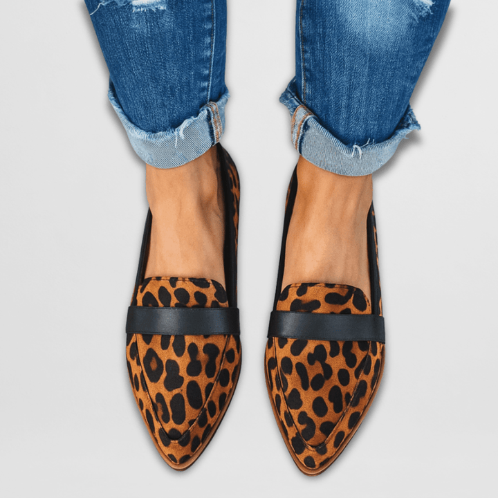 A woman wearing warm tan pointed-toe loafers with cuffed cropped jeans.