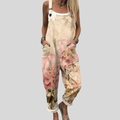Woman wearing cream overalls printed with large watercolour roses in soft pink and peach, standing relaxed.