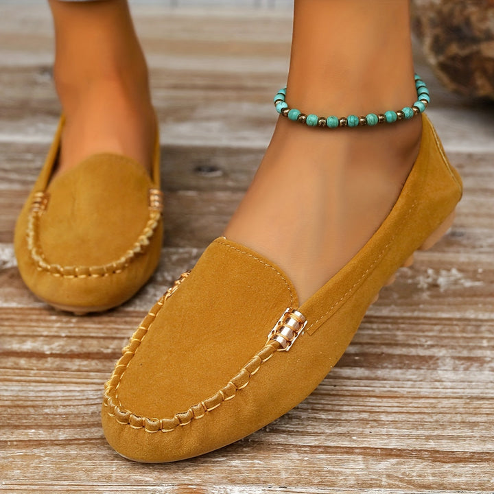 A woman in a ballet-flat loafer stepping lightly along a bright pavement.