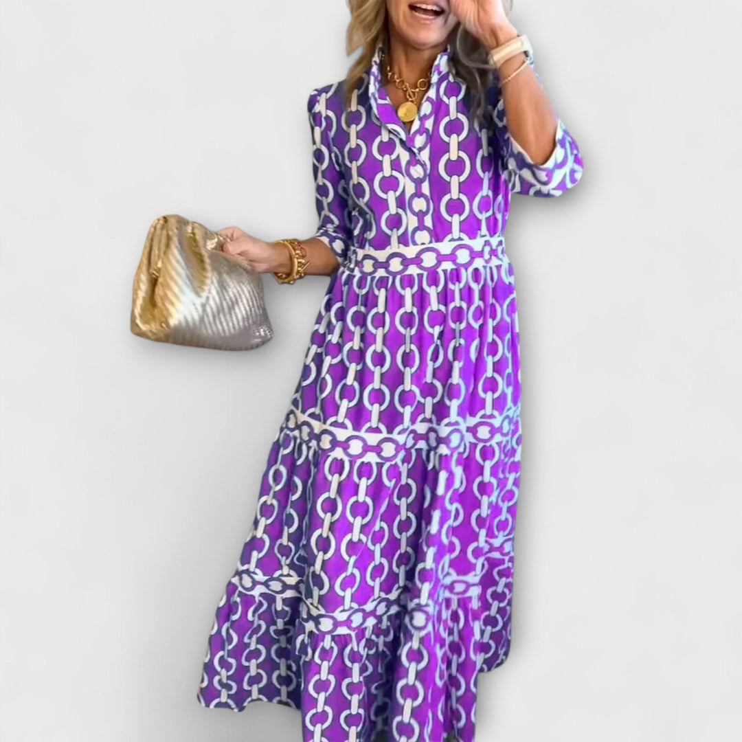 A woman wearing a flowing chain print midi dress that drapes elegantly as she walks.
