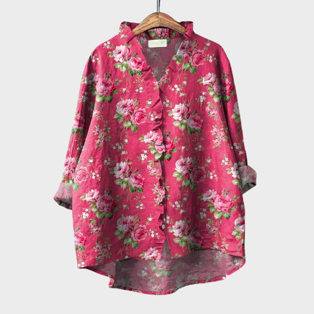 A woman wearing an elegant pink patterned summer blouse with a fluttering cut, styled with jeans.